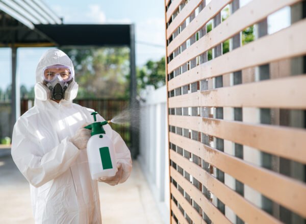 Disinfection specialist staff in personal protective equipment (ppe) suit, gloves, mask and face shield, cleaning Quarantine area with a bottle of pressurized spray disinfectant to remove covid-19.